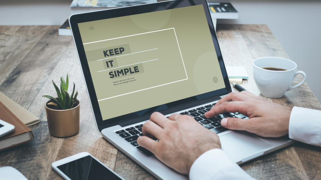 Hands typing on laptop. Photo displayed on laptop screen reads "keep it simple."